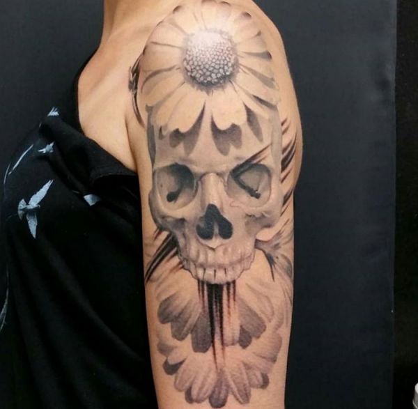 Totenkopf und Gänseblümchen Tattoo am Oberarm