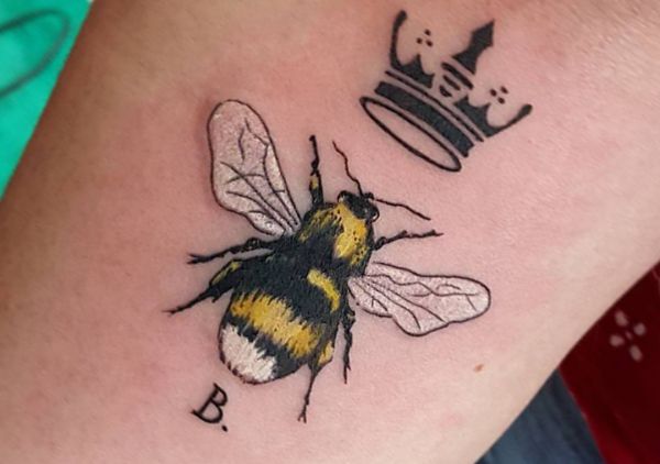 Bienenkönigin mit Krone und Initialen auf dem Arm