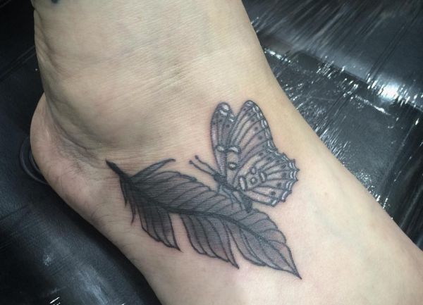Feder mit Schmetterling Tattoo am Fuß für Frau