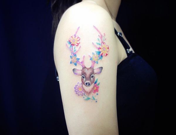 Hirschkopf mit Blumen Tattoo Design am Oberarm Frau
