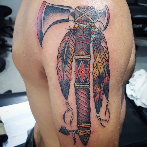 Axt mit Indianer Federn Tattoo auf dem Arm