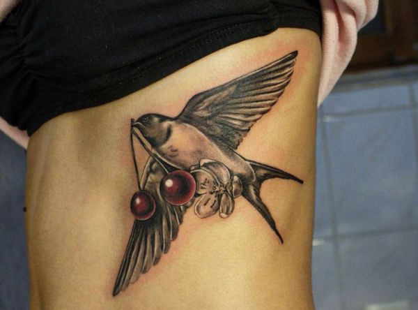 Schwalbe Tattoo mit Kirsche am Rippenbogen