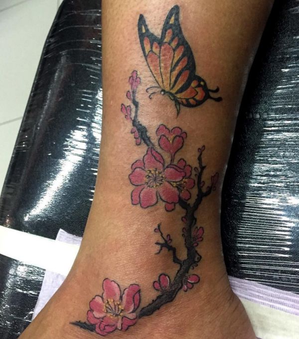 Schmetterling mit Blumen Tattoo am Unterschenkel