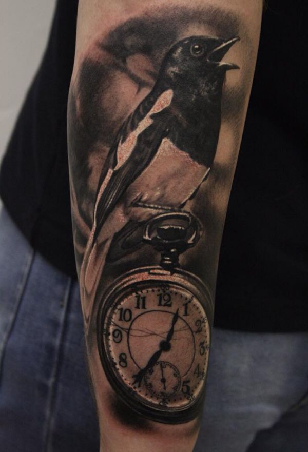Elster und Uhr Tattoo auf dem Arm