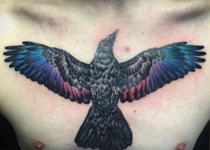 Rabe Tattoo mit Bunte Feder auf der Brust