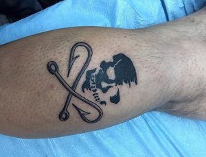 Zwei Haken Tattoo mit Totenkopf am Unterschenkel