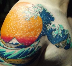 Japanische Wellen Tattoo mit Blumen am Oberarm