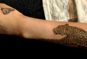 Leopard mit Schmetterling auf dem Arm