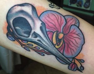 Orchidee Tattoo mit Kolibri Schädel Design auf dem Arm
