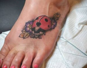 Marienkäfer mit Blumen Tattoo am fuß