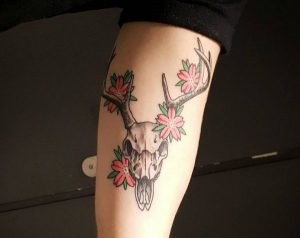 Hirsch Totenkopf mit Blumen Tattoo am Oberarm