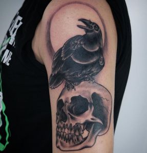 Totenkopf und Rabe Tattoo am Oberarm