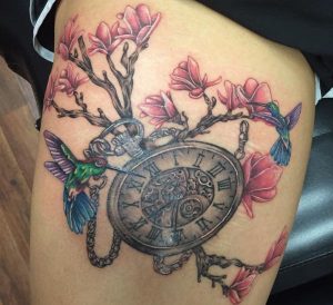 Antike Uhr Tattoo mit Kolibri und Blumen am Oberschenkel